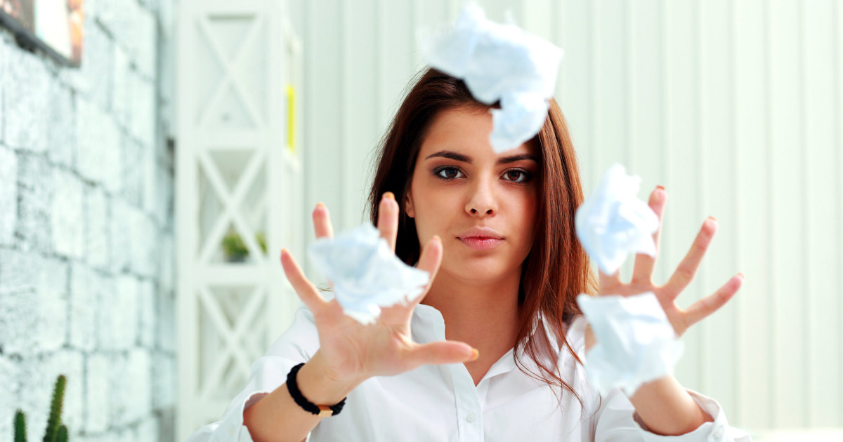stock photo of a young professional woman frustrated and throwing paper at the camera