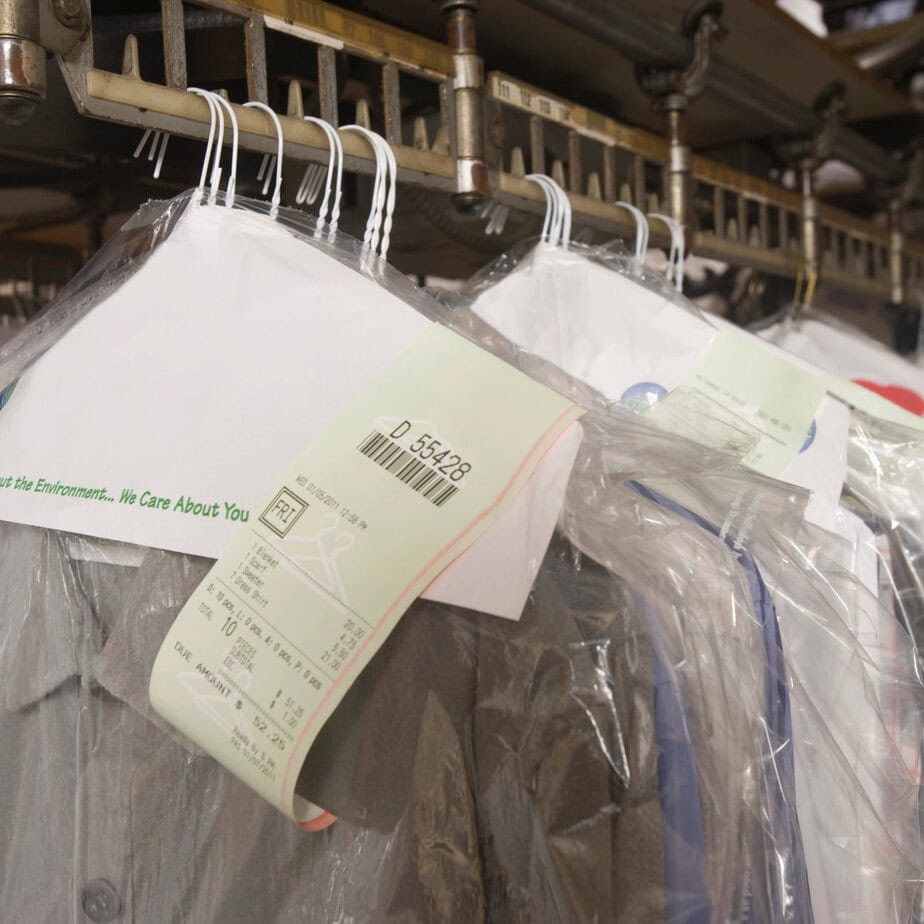 Clothes hanging on a rack with tags at a dry cleaner for cleaning and maintenance.