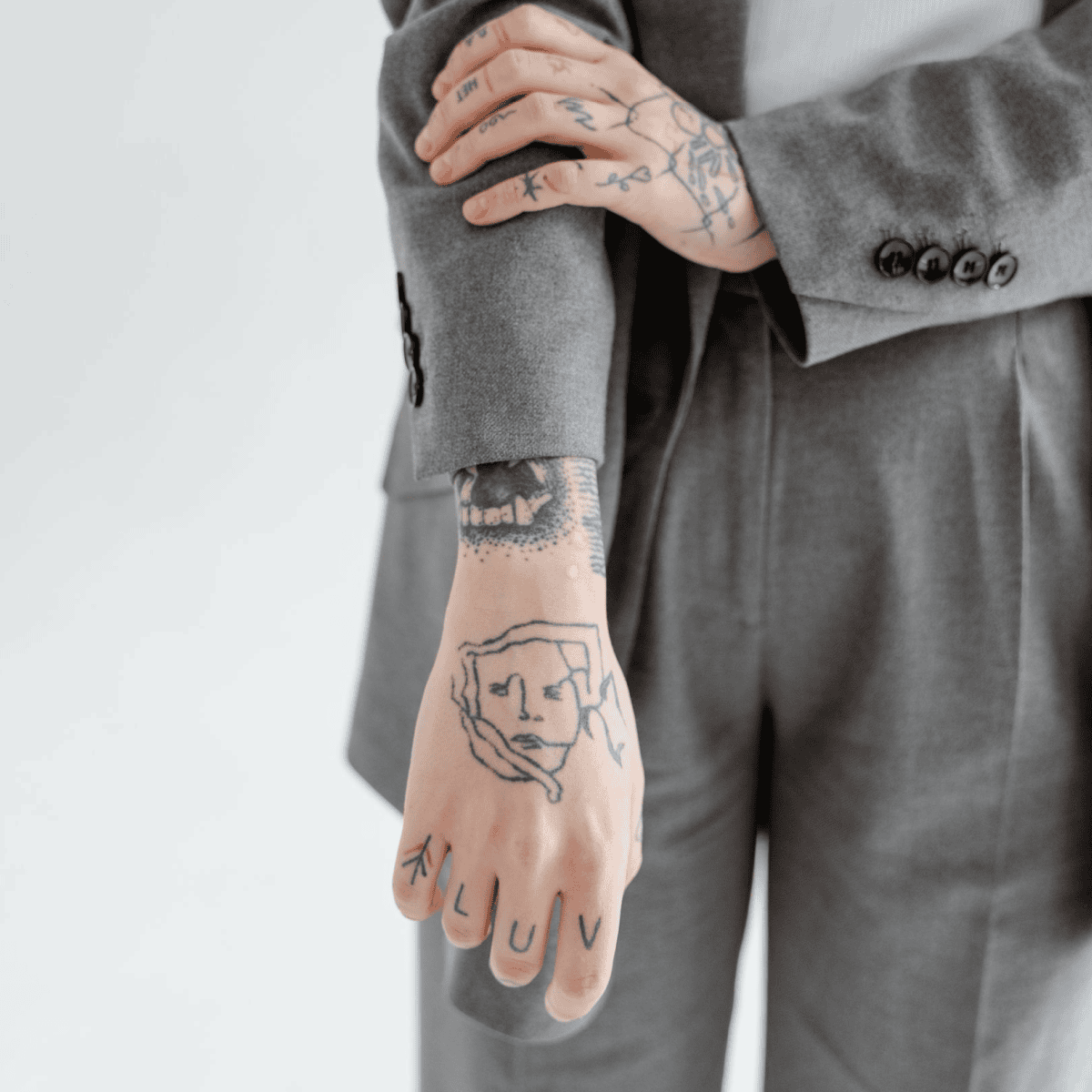 tattoos in the workplace woman in suit pushes up her blazer sleeve to reveal tattoos on her arm and hand