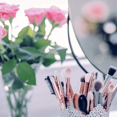 makeup brushes and flowers on a counter