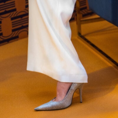 woman wears silvery pewter shoes with white wide-leg pants