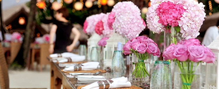 a long table with place settings and multiple pink flowers 