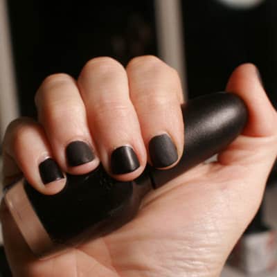 photo of woman's hands wearing black nail polish; she is holding a black nail polish bottle and trying to show personality at the office