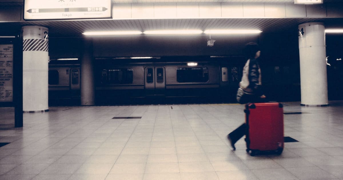 professional woman walks with a packed suitcase; she might be walking in the underground NYC subway system