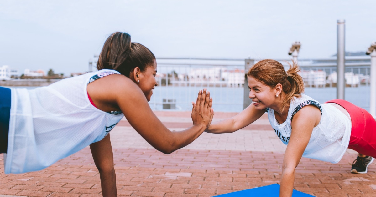 two young professional women high-fiving while doing planks