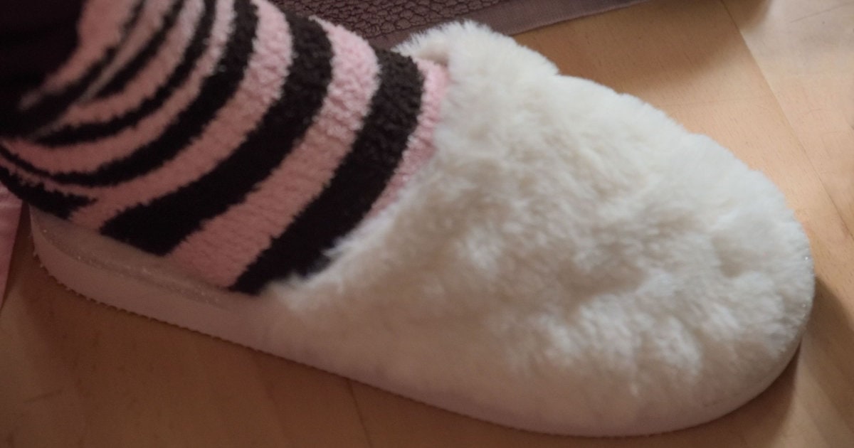 person wears pink stripey socks with fuzzy slippers