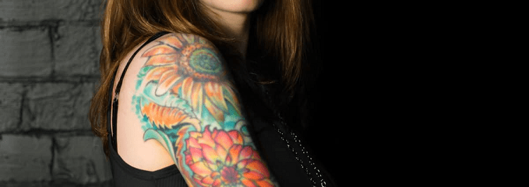 model in black tank with colorful tattoos on her arm