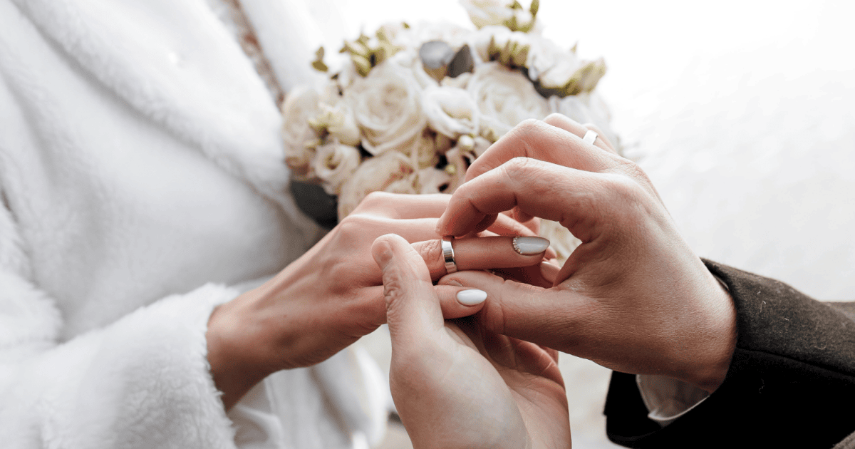 Alt: Man placing a wedding ring on a woman's finger during a wedding ceremony