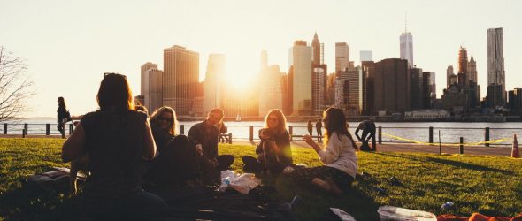 group of young professionals eating outdoors at sunset; they may be attending a company picnic
