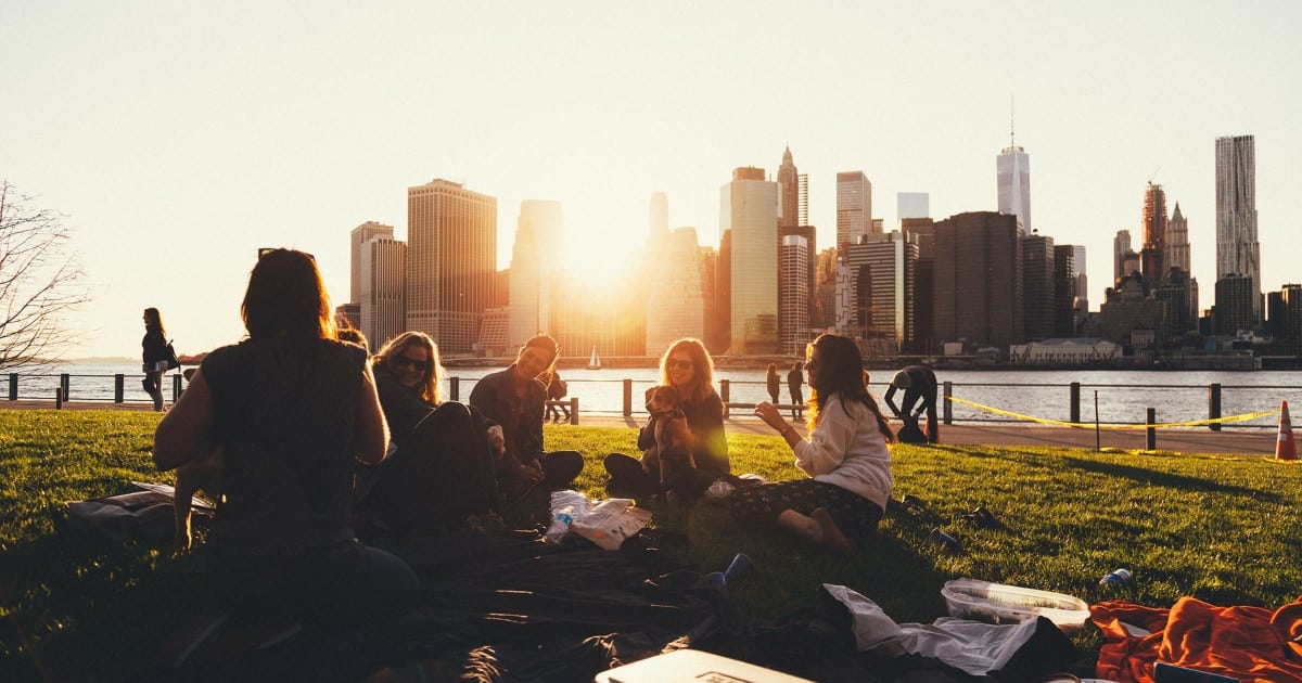 group of young professionals eating outdoors at sunset; they may be attending a company picnic