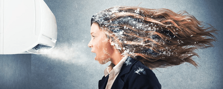 professional young woman wearing a suit standing in front of wall AC unit getting frost in her hair and on her clothes