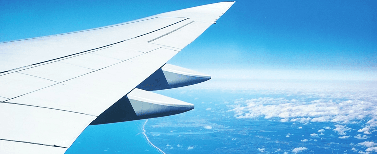 view outside plane window of wing flying over an ocean