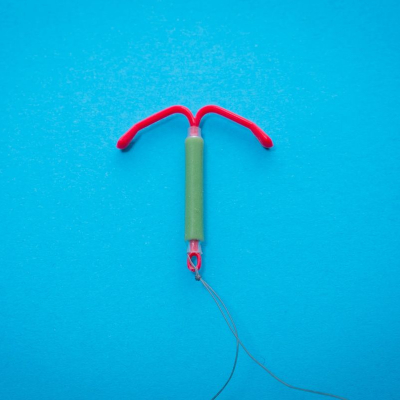 a red IUD is laid against a bright blue background