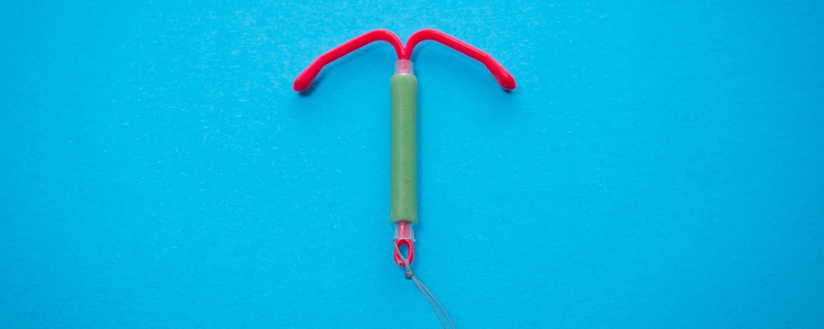 1 a red IUD is laid against a bright blue background