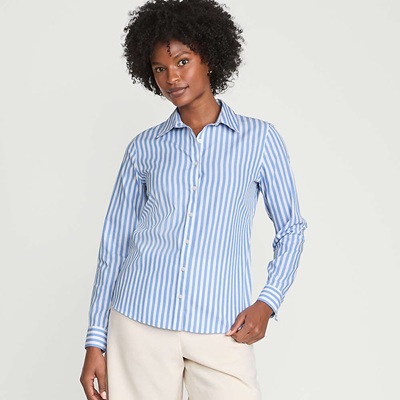 A woman wearing a blue-and-white pinstripe blouse and off-white pants