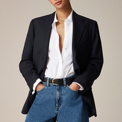 stylish executive wears white button-down shirt beneath a black blazer; she has it tucked into blue jeans
