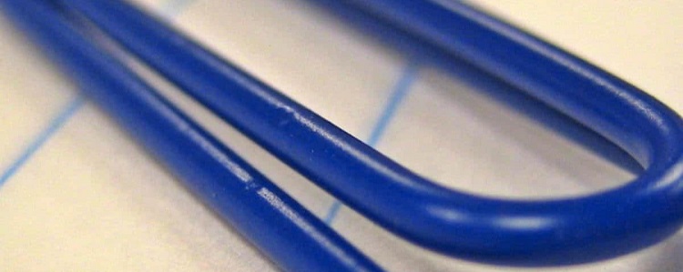 close-up of blue paperclip against lined paper