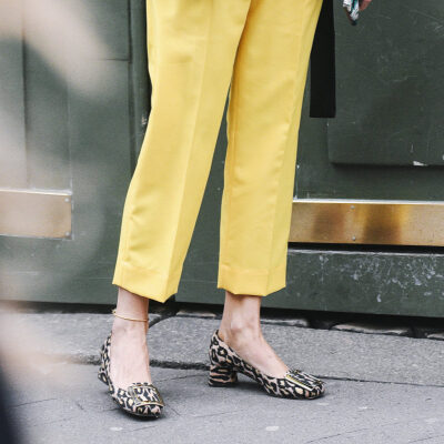 woman wears animal print pumps with bright yellow cropped pants