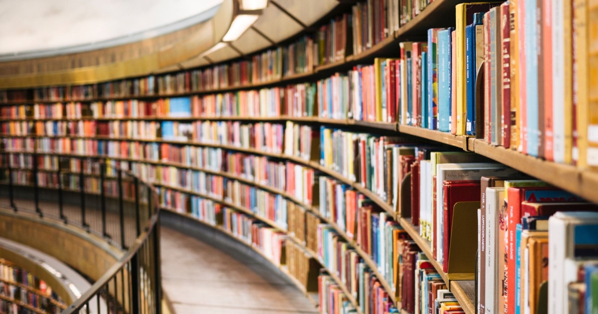 a curved wall with lots of books, possibly at a business school's library