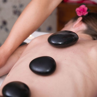 woman getting hot stone massage; heated black stones are on a naked woman's back 
