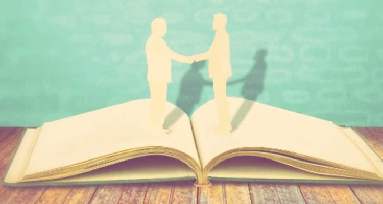 artistic rendering of two people shaking hands and possibly one is a woman building her book of business -- the figures look like cardboard cutouts sitting on top of an open book.