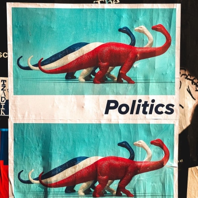 wrinkled poster shows 3 dinosaurs in blue, white and red looking behind them; the poster reads "Politics"