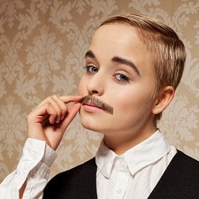 woman with short hair pulls off a false mustache 