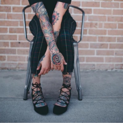 young woman in pinstriped pants with prominent tattoos on her feet
