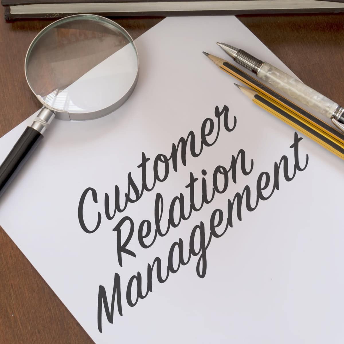 paper on table says "Customer Relation Management" in cursive
