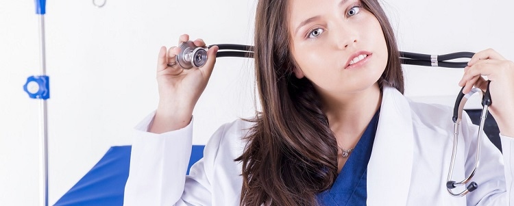 Female doctor in a white coat wearing hair bonnet and mouth guard