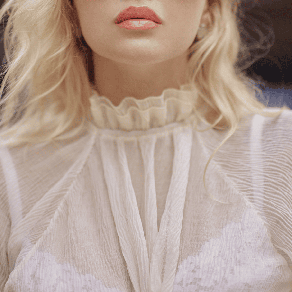 woman wears white frilly blouse with white lacy camisole beneath it