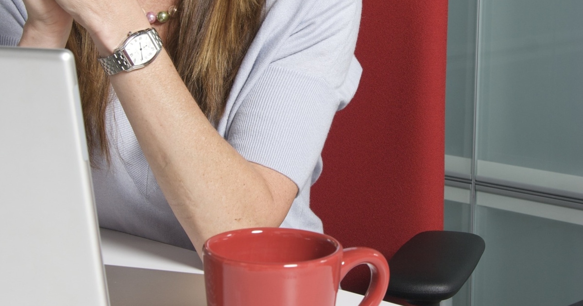 corporate woman sits in red office chair in front of computer - is it ergonomically comfortable for petites? 