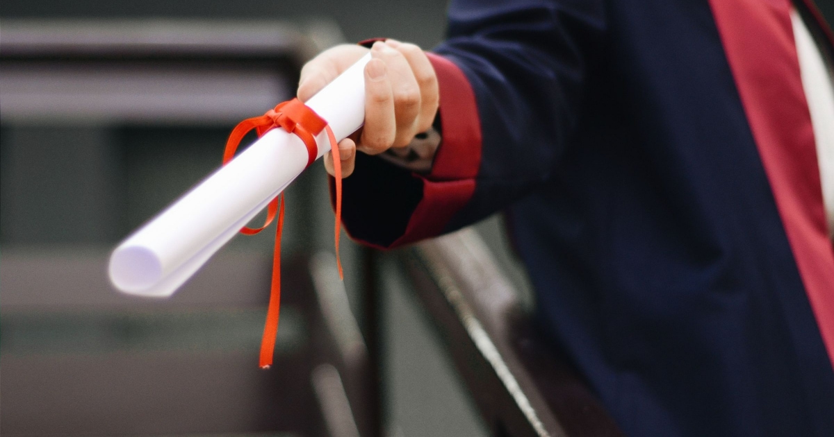 woman receiving MBA degree bound with red ribbon