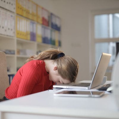 professional woman rests her head on her laptop; she is wondering when to quit your career