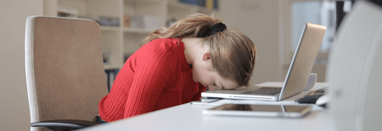 professional woman rests her head on her laptop; she is wondering when to quit your career