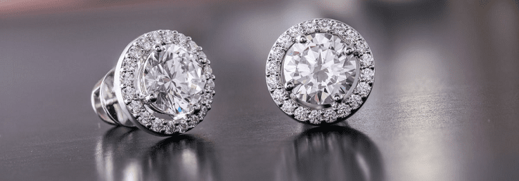 two diamond earrings sit on a table