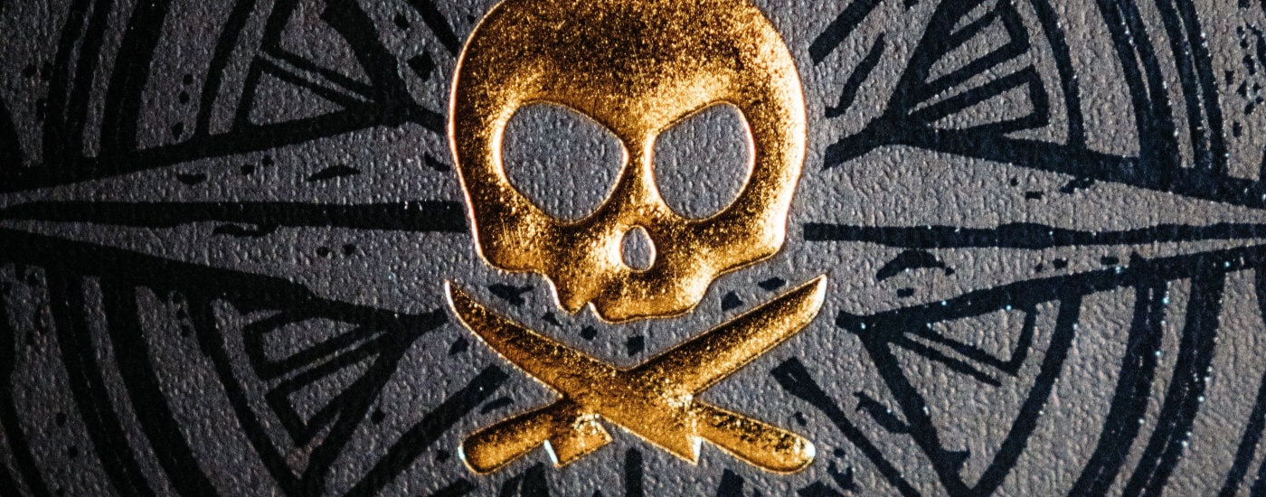 gold pirate icon against a black compass-type star design