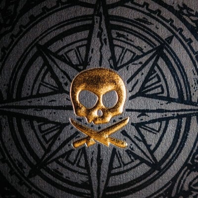 gold pirate icon against a black compass-type star design