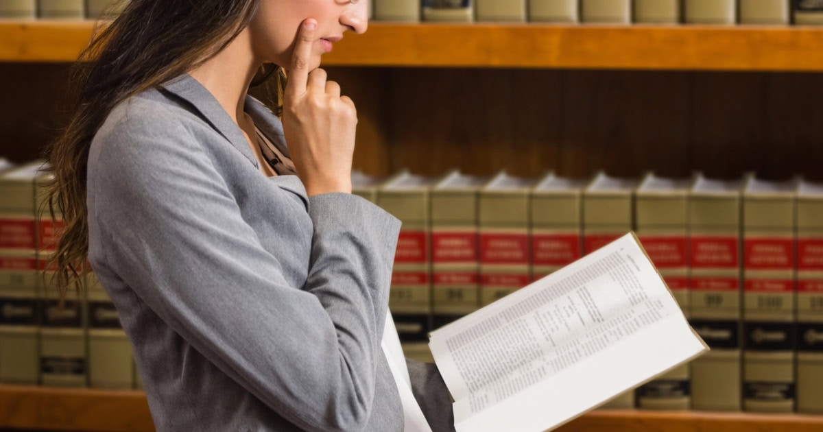 woman studiously looks at a lawbook (probably the federal reporter)