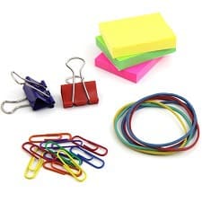 office supplies such as neon post-its, binder clips, paper clips, and rubberbands spread across a white desk