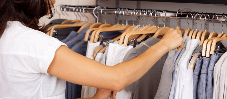 white woman wearing white shirt hunting for shirt from rack in clothing store