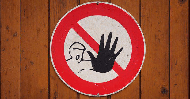 circular sign with a red circle and a red slash through the center of the circle; the sign features a person holding up a hand to say STOP