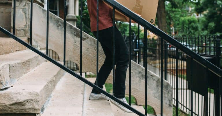 person is carrying a box down the front stoop steps