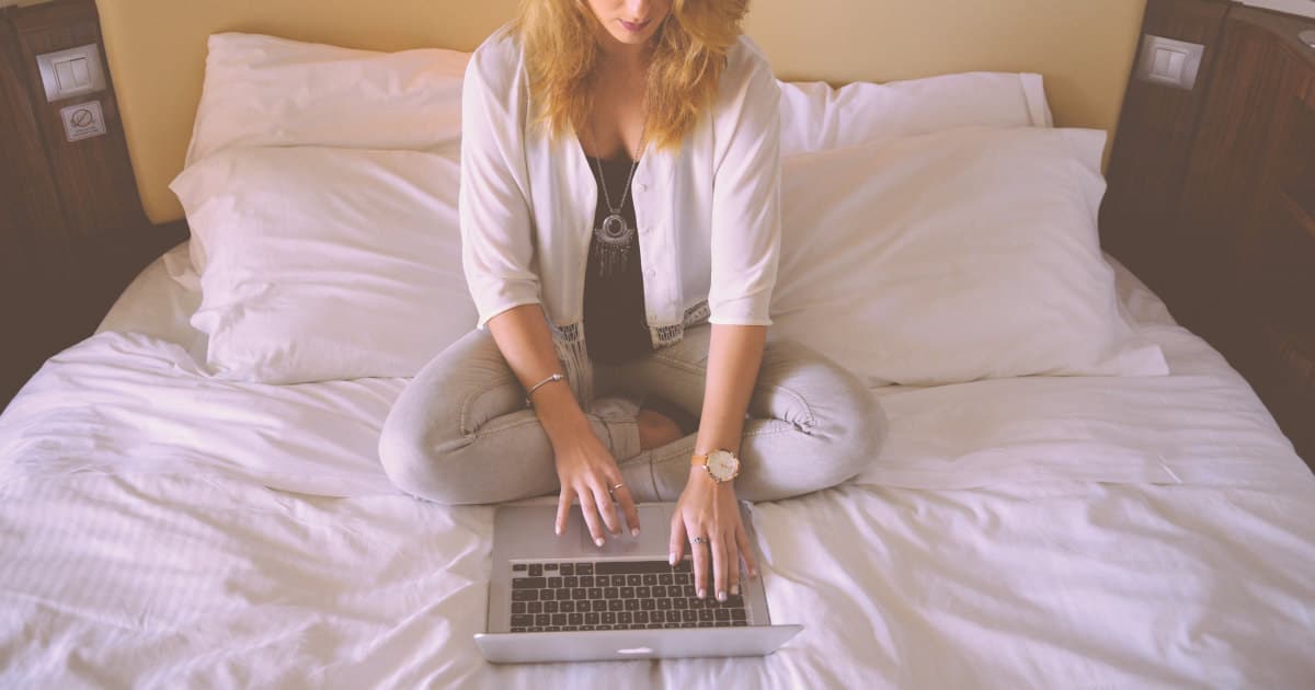 professional woman typing on laptop in bed