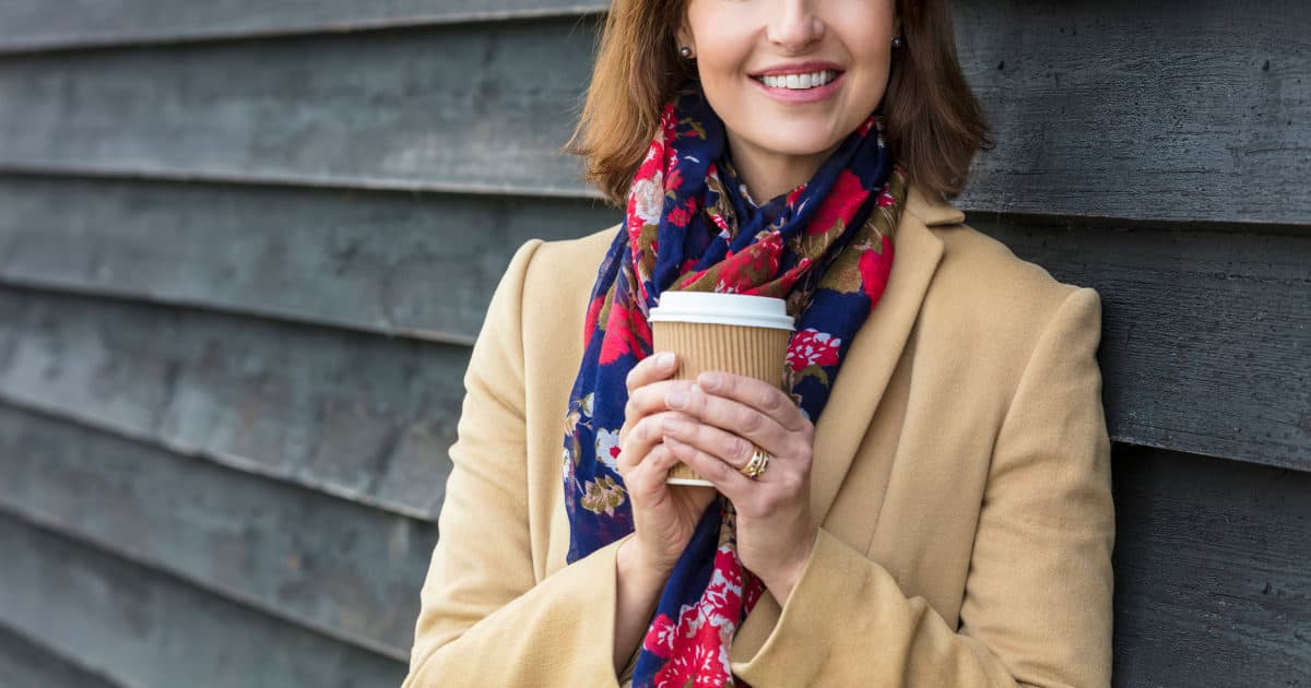 professional woman wearing a stylish coat and holding a cup of coffee