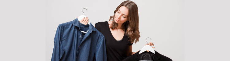 young professional woman gazing at different work outfits on hangers