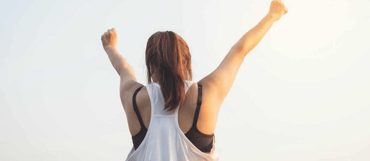 woman in exercise clothes raising her fists in victory
