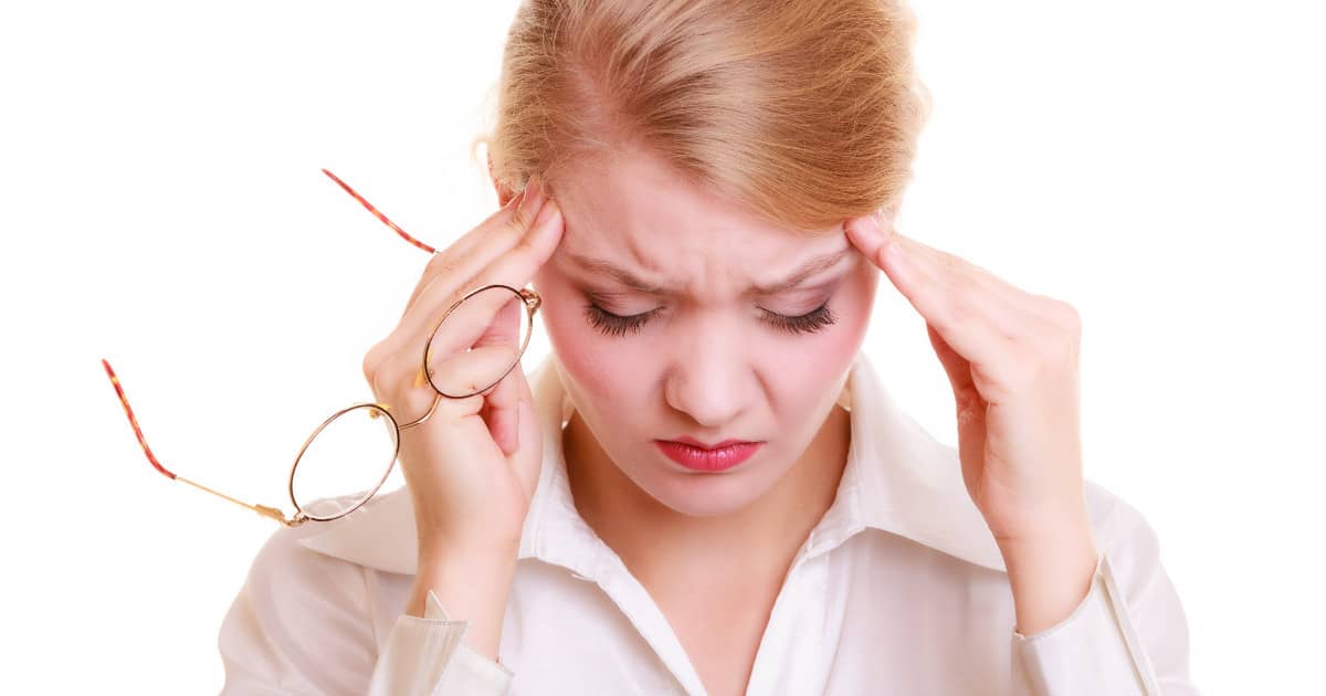 blond woman rubbing her temples and holding her eyeglasses