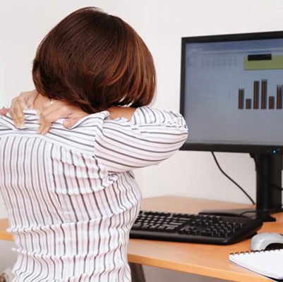 woman looking at a computer and rubbing her shoulders