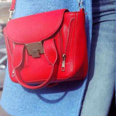 woman with blue coat wears a red handbag that looks like a 3.1 Philip Lim